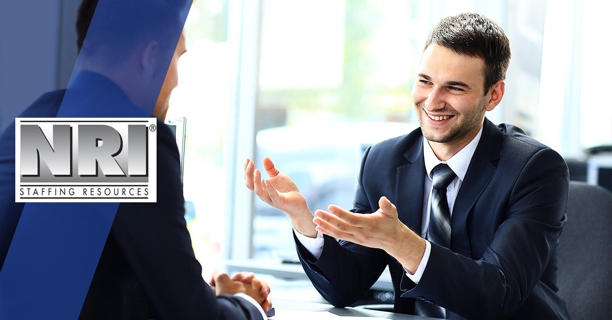 young man in a suit smiling ans gesturing in his interview