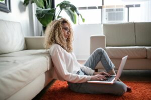 Recent graduate searching for first job out of college staffing agency openings on her laptop at home.