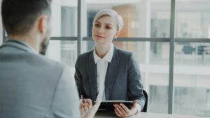 how to find a job through a staffing agency — recruiter interviewing a candidate at an office desk
