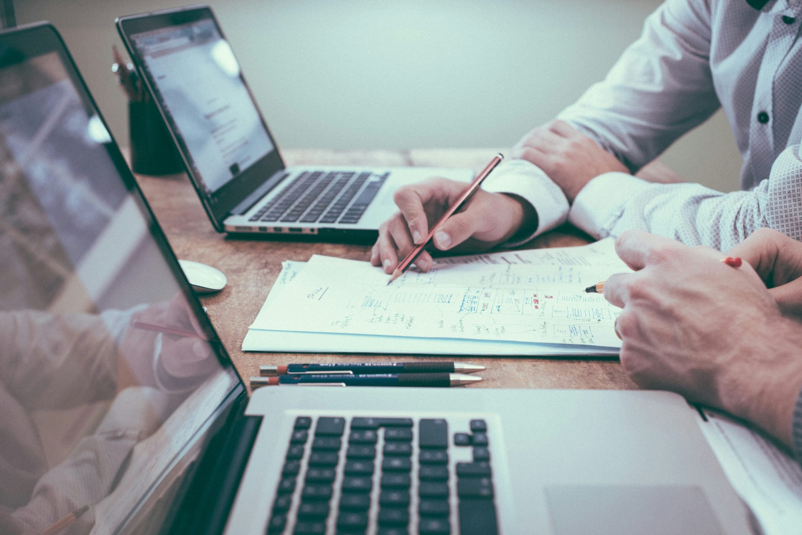 401k first job new graduate — two professionals reviewing retirement plan documents and financial paperwork at a desk with laptops