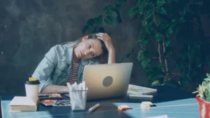 A hiring manager overwhelmed at a laptop by a flood of AI resumes.