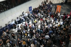 A busy conference floor with registration tables and exhibitor booths that rely on temporary event staff.